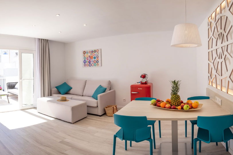 Living area with small red fridge, two-seater sofa and dining table