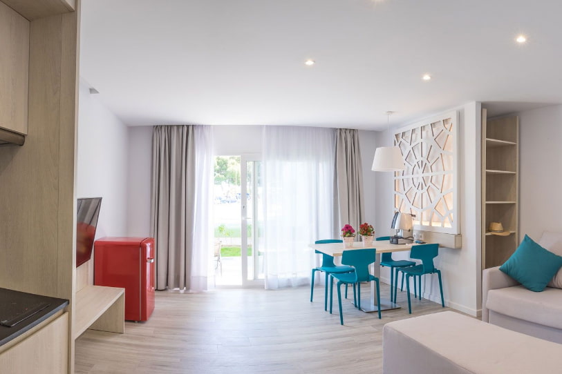 Bright living area with large windows, red fridge and table